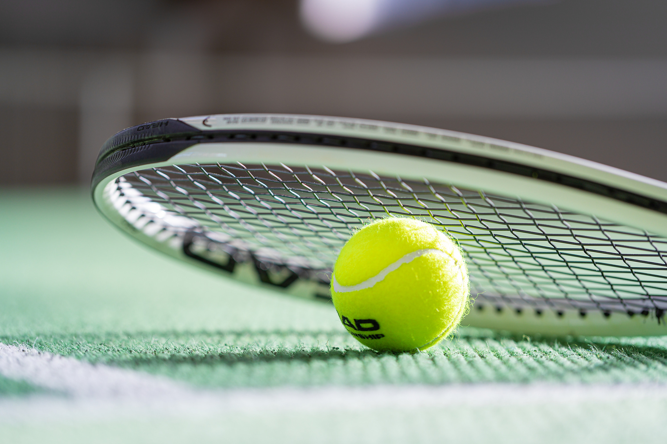 Tennisschläger mit Tennisball am Teppich-Granulat liegend