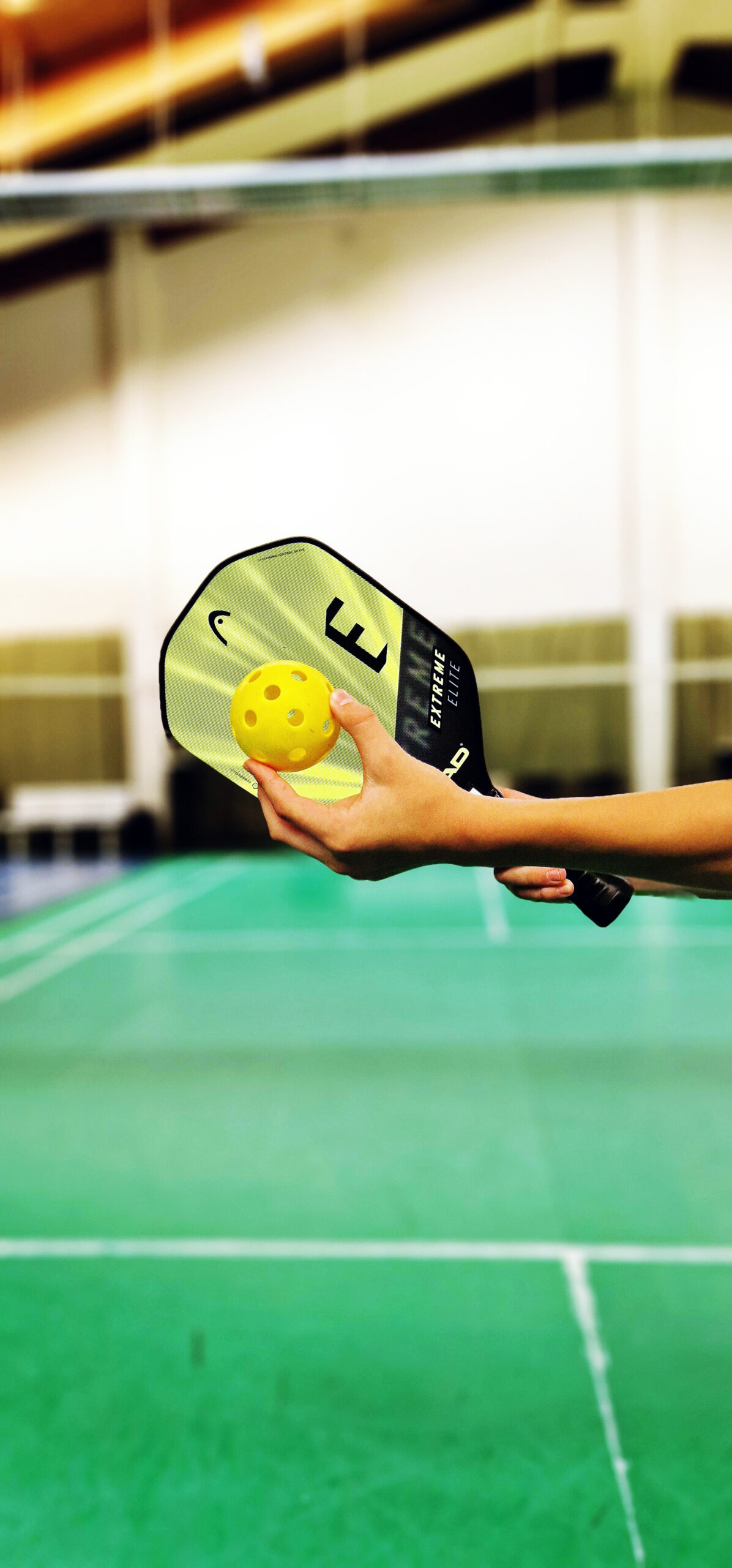 linke Hand, die einen Pickleball hält, rechte Hand hält ein Picklelball Paddle