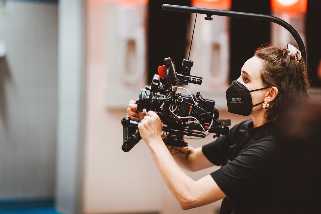 Kamerafrau mit Maske und Kamera und Kamerstütze